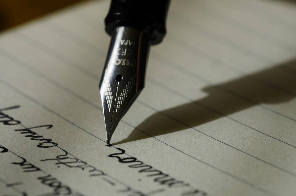 ilustrasi pena dan kertas yang sudah berisi tulisan (unsplash/Aaron Burden)